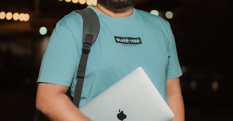 Laptop Stand - A man in a blue shirt holding a laptop