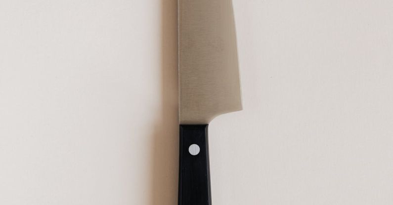 Cutting Tools - Top view of large black handle knife with sharp blade for cutting products and cooking food placed on gray kitchen table